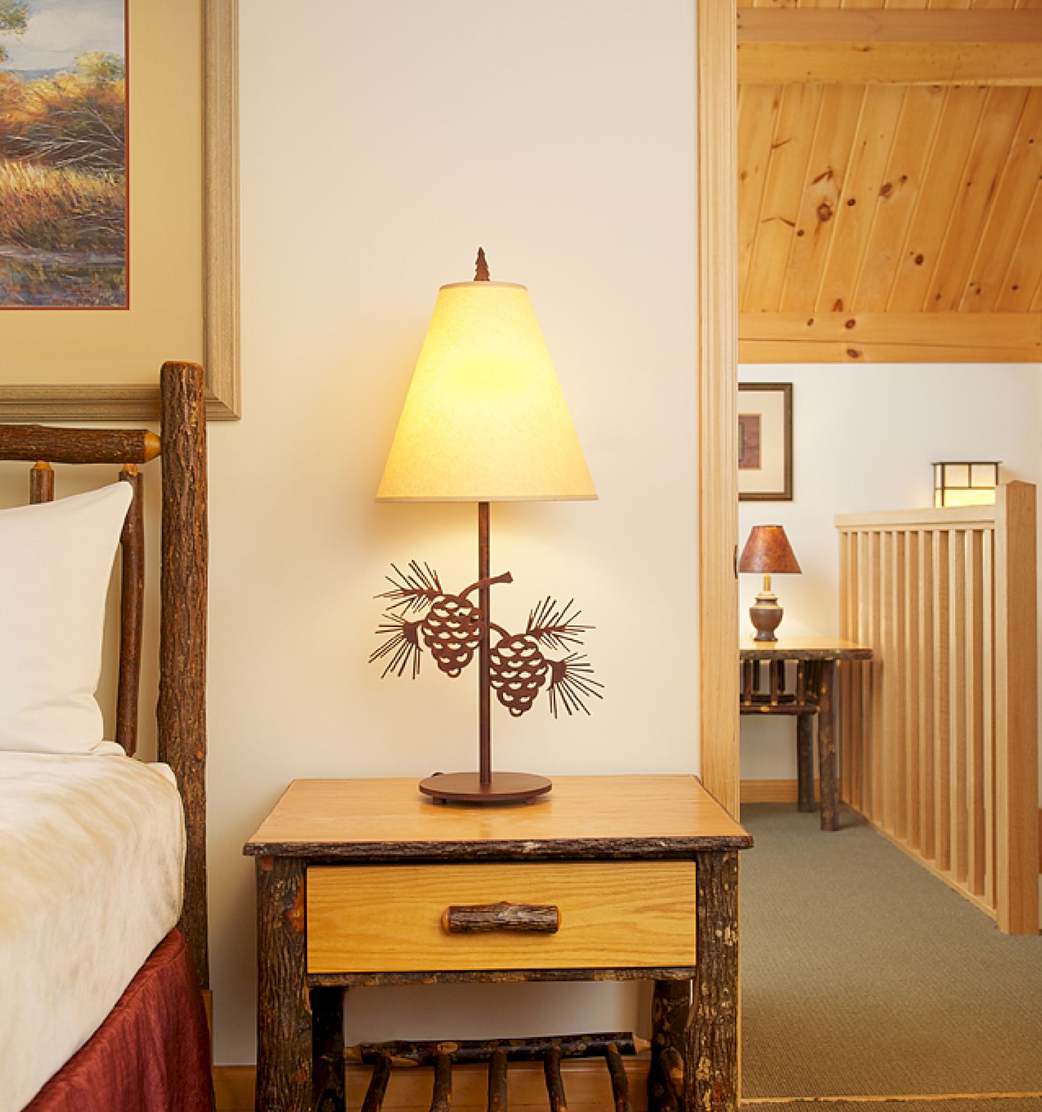 The image depicts a cozy bedroom with a rustic nightstand, lamp, and bed, adjacent to a hallway shown in the background, ending the sentence.